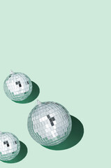 Shiny silver disco balls over green background. Creative Christmas pattern. 90s retro party time...
