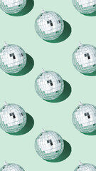 Shiny silver disco balls over green background. Creative Christmas pattern. 90s retro party time concept. Xmas holiday background. Top view. Flat lay.