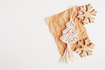 Christmas tree macrame toys on craft papper. White background. Natural materials - cotton thread, wood beads and stick. Eco decorations, ornaments, hand made decor. Winter and New Year holidays.