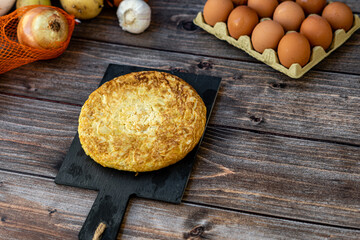 Top view, still life. Spanish potato omelette with some ingredients, on a wooden background. Copyspace