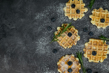 Homemade viennese waffles with blueberries, rosemary on dark background. Copy space background.
