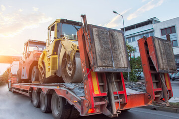 Heavy road equipment asphalt compactor loaded and transported on a truck trailer