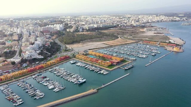 Portimao - Algarve - Portugal. Cinematic aerial view of Portimao marina. At left, famous Praia da Rocha. In background, panoramic view of the city. Travel destination in Portugal. Drone truck left