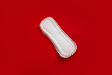 A sanitary pad lies on a red background. Menstrual cycle and pregnancy. Negative pregnancy test and contraceptives. Sanitary napkin