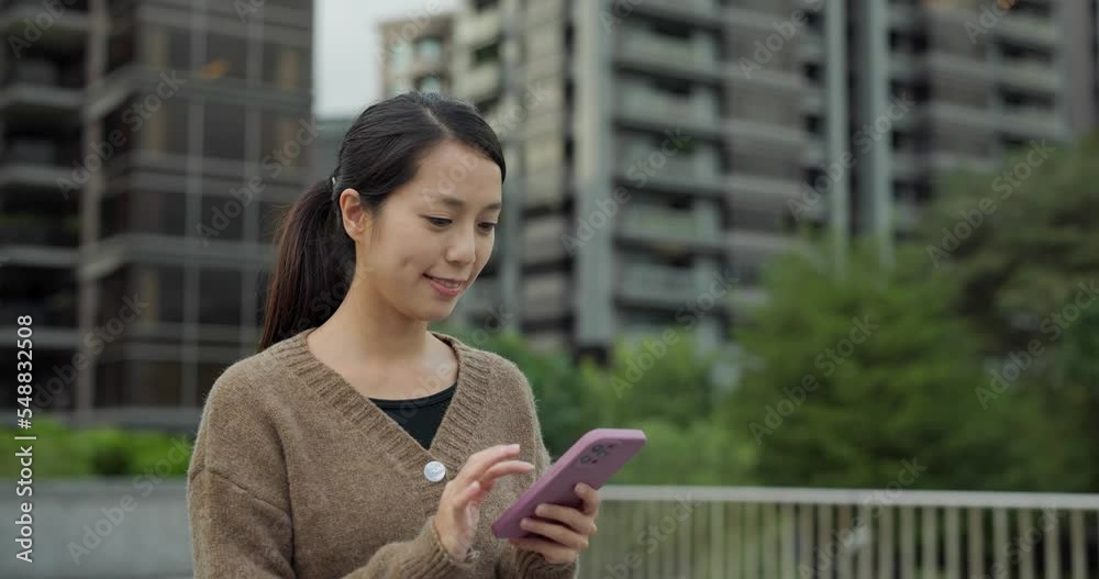 Poster woman walk in the street and look at mobile phone in the taipei city with background of building