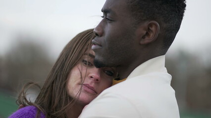 Fototapeta premium Caring interracial couple hugging outside. Young millennial embrace and hug