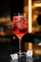cocktail with ice cubes on black bar counter