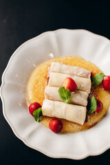 Pancakes with cherries on a crème brûlée pillow, decorated with powdered sugar.
