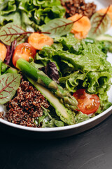 Bowl with salmon, quinoa and asparagus, garnished with tomatoes and herbs. Concept of healthy eating.