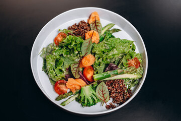Bowl with salmon, quinoa and asparagus, garnished with tomatoes and herbs. Concept of healthy eating.