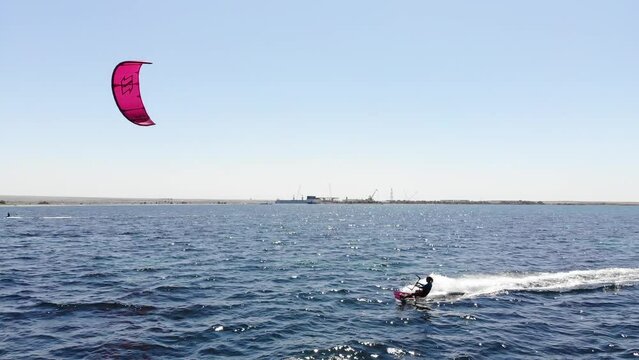 Aerial view of a young caucasian sportswoman cruising on her kitesurf in the open sea on a sunny day