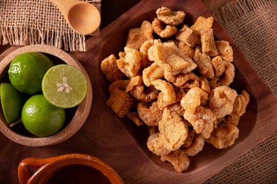 Chicharrones. Deep fried pork rinds, crispy pork skin pieces, traditional mexican ingredient or snack served with lemon juice and red hot chili sauce.