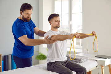 Physiotherapy specialist and his male patient use special equipment during rehabilitation. Young...