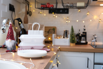Food delivery service containers on table white scandi festive kitchen in christmas decor. Eve New year, saving time, too lazy to cook, hot order, disposable plastic box in fairy light. mock up