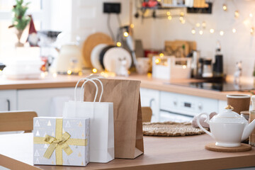 Gift box and packages are on kitchen table decorated for Christmas. Present and ready meals are delivered and prepared for the new year