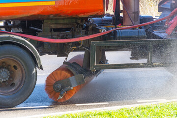 Sweepers wash the urban asphalt road with rotating brushes.