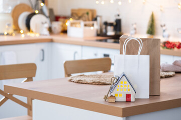 Key to the house on cozy home with Christmas decor and packages on table of festive kitchen. Gift for New Year. Building, design, project, moving to new house, mortgage, rent and purchase real estate