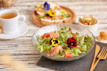 Fototapeta na wymiar Healthy Mediterranean pescetarian salad with smoked salmon, vegetables, greens and edible flowers. Tea with appetizers. Healthy dinner.