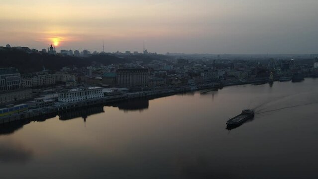 Kyiv, Ukraine - Evening aerial view with sunset and pink sky on barge and Podil from the river Dnipro 4k