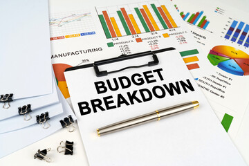 On the table among financial graphs and charts lies a tablet with the inscription - BUDGET BREAKDOWN