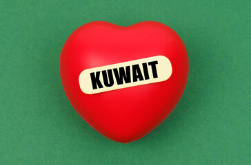 On a green surface lies a red heart with the inscription - Kuwait