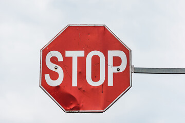 Close up to a stop road sign on a pillar against a clear sky