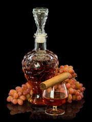 A decanter and a glass filled with cognac, a cigar and a bunch of grapes