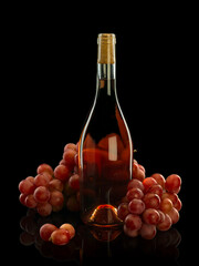 A bottle of wine and a bunch of grapes