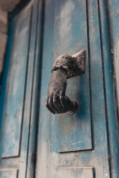 Puerta azul con una aldaba en forma de mano 