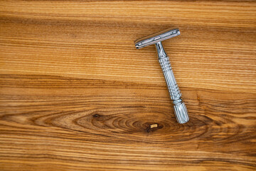 T-shaped razor on a wooden table. Top view