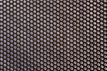 background of perforated rusty metal wall with dots, stucco wall behind