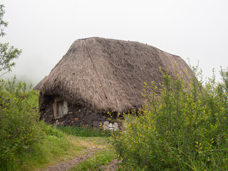 Vistas de una casa tiípica en la Braña de Pornacal, de Asturias, con techo de paja en verano, un...