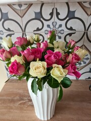 bouquet of pink and white roses in a white vase  on wood table on the kitchen