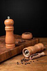 Pepper mill and whole pepper in wooden scoop on wood table. © stenkovlad
