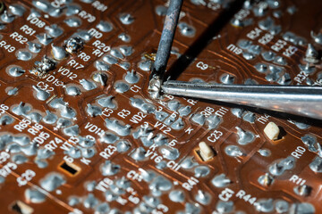 Old printed circuit board with soldering iron. Vintage circuit board with soldering trace ....