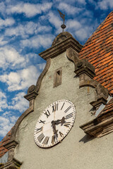 Detail of a building with a big old clock on the roof on a sunny day on a blue sky background, closeup. West Ukraine
