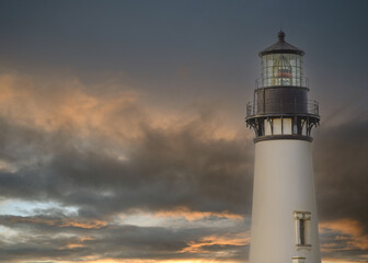 Beautiful white lighthouse against the sky with thunderclouds. Twilight. Beautiful landscape. Maritime navigation, architecture, construction, travel, tourism, weather, ecology.