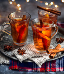 Hot drink for New Year, Christmas or autumn holidays. Mulled cider or spiced punch, tea or mulled white wine with lemon, apples, cinnamon, anise, cloves on a dark background. No People.