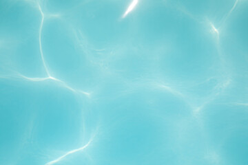 Background, blue water waves in the pool with sun reflection. Top view, selective focus