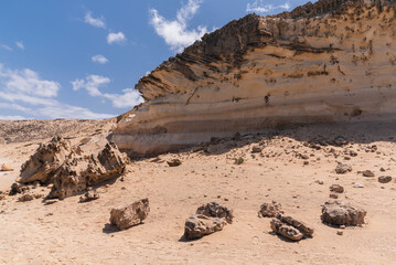Majestic high cliff made of white to brown rock with many small holes, west coast Fuerteventura, Canary Islands 
