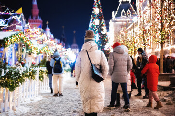 Moscow, Russia - January 7, 2022: Girl walks near GUM on Red Square near the Kremlin. New Year decorations and Christmas atmosphere on a winter street in Moscow.