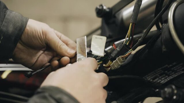 A mechanic cleans electrical wires from insulation to repair electrical equipment in a motorcycle. Close-up. Transport concept
