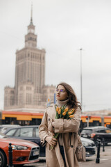 A young girl in glasses with flowers against the background of the Palace of Culture in Warsaw. A...