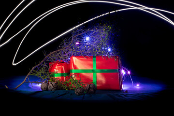 christmas and new year background - gift boxes and pine branches on lights background and copy space over dark wall with lights