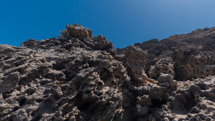Dry dark desert full or rocks with holes during hot sunny day, Canary Islands