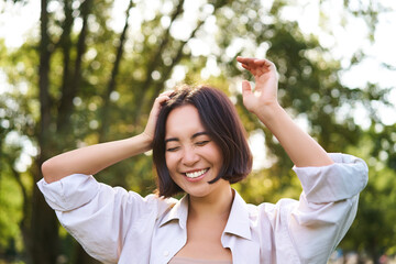 People and emotions concept. Happy asian woman laughing and smiling, posing on summer day in park