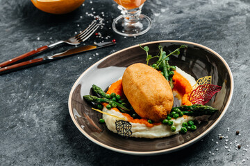 Chicken Kiev cutlet breast stuffed with butter, garlic and herbs served with asparagus and peas. Food recipe background. Close up