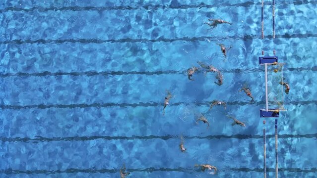 Aerial drone top view of swimming pool with athletes training water polo