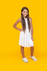 glad teen kid in white dress standing on yellow background
