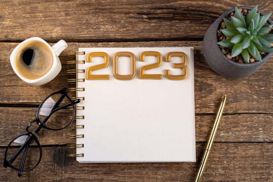 New year resolutions 2023 on desk. 2023 resolutions list with notebook, coffee cup on table. Goals, resolutions, plan, action concept. New Year 2023 background. Copy space